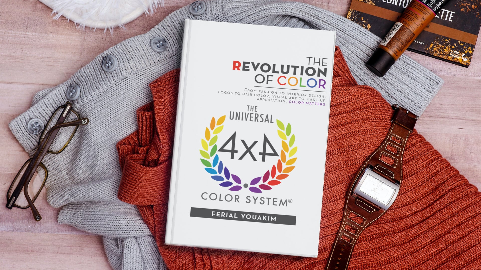 revolution of color book placed on top of clothes with watch, eyeglasses and makeup on the side